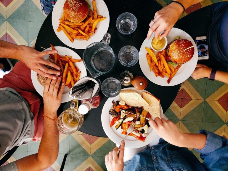 Late Night Food In Columbus: 9 Spots That Are Actually Open Late 2 Overhead view of three people sharing burgers, fries, and drinks at a colorful tiled table.