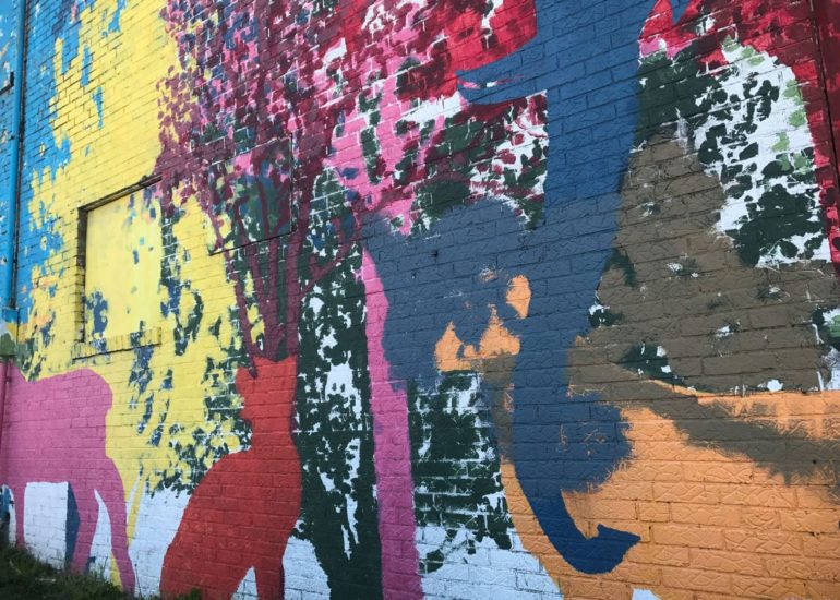 Weathered mural with colorful animal silhouettes including a deer