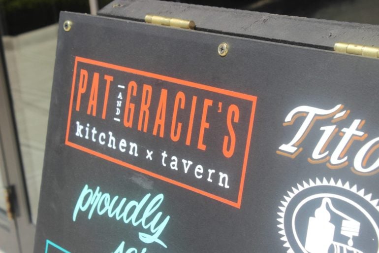Close-up of Pat Gracie's kitchen and tavern restaurant sign with orange and white lettering.