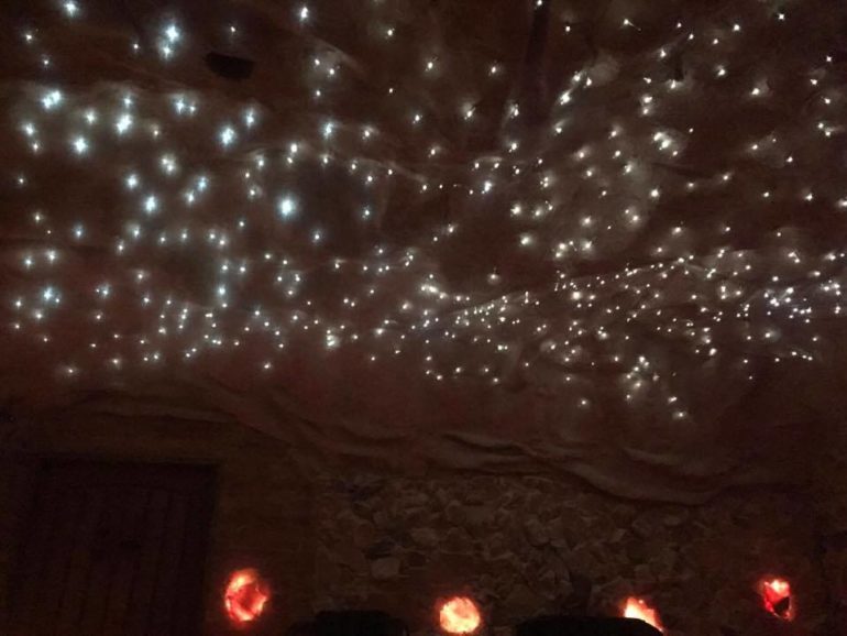 Starlit cave ceiling with tiny lights and warm glowing orbs below