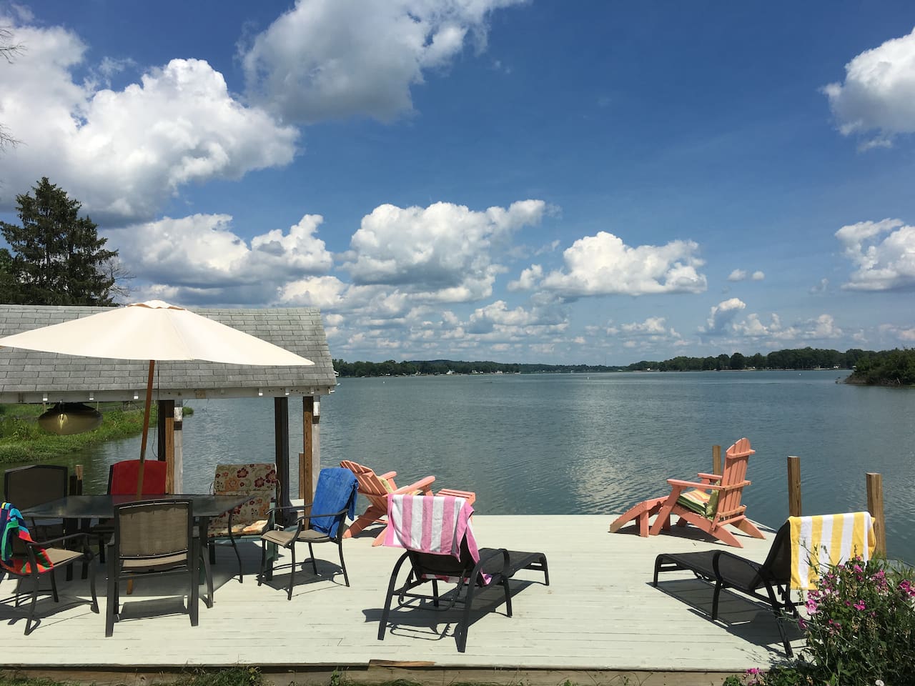 Lakefront deck with patio furniture, umbrella, and chairs overlooking Buckeye Lake