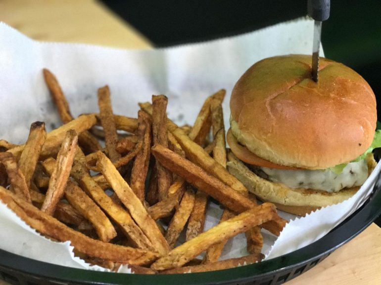A Burger From This Whitehall Restaurant Will Change Your Life, Especially If You Get The Spicy Sauce 2 Burger with lettuce and cheese, skewer pin on top, beside crispy fries in basket
