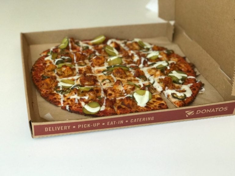 A Donatos pizza in a cardboard box topped with meat, cheese, and pickled vegetables.