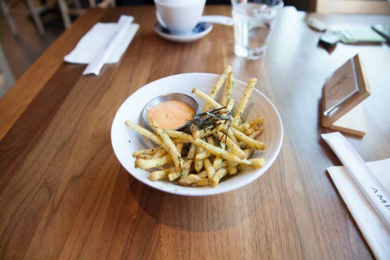 The Most Delicious French Fries Columbus Has To Offer 8 Golden seasoned fries with dipping sauce served on white plate at restaurant table
