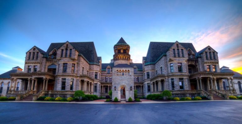 This Storied Ohio Reformatory Is The Place For Chills And Thrills 12 Grand Victorian mansion with ornate stone architecture and central tower at dusk.
