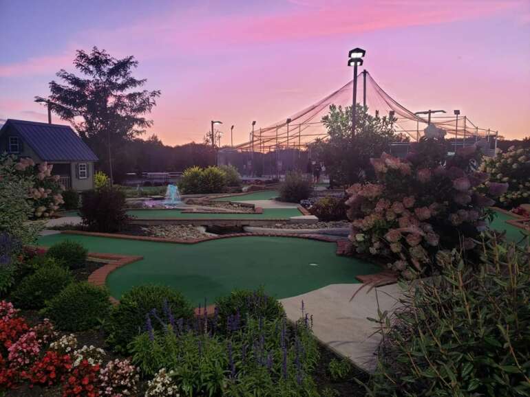 The 9 Best Miniature Golf Courses In Columbus 13 Landscaped mini-golf course at dusk with batting cages behind it