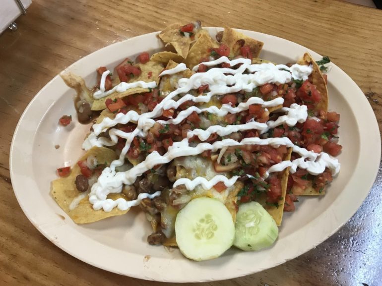 Los Guachos Tacos Al Pastor Are The Best In Town, Especially On 2-For-1 Mondays 3 Nachos topped with cheese, beans, pico de gallo, sour cream drizzle, and cucumber slices