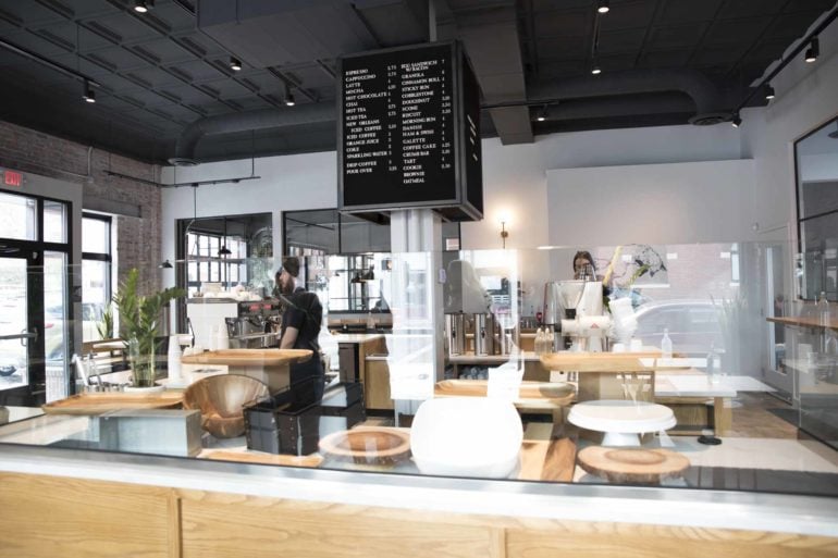 Fox in the Snow interior with menu board, counter seating, and baristas preparing beverages.