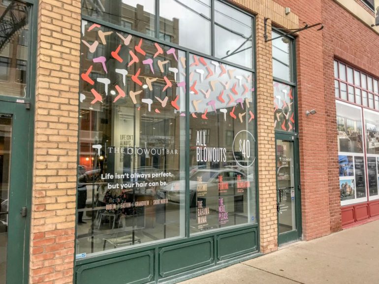 Blowout Bar storefront window with colorful hair-dryer decals and $40 blowout pricing signage