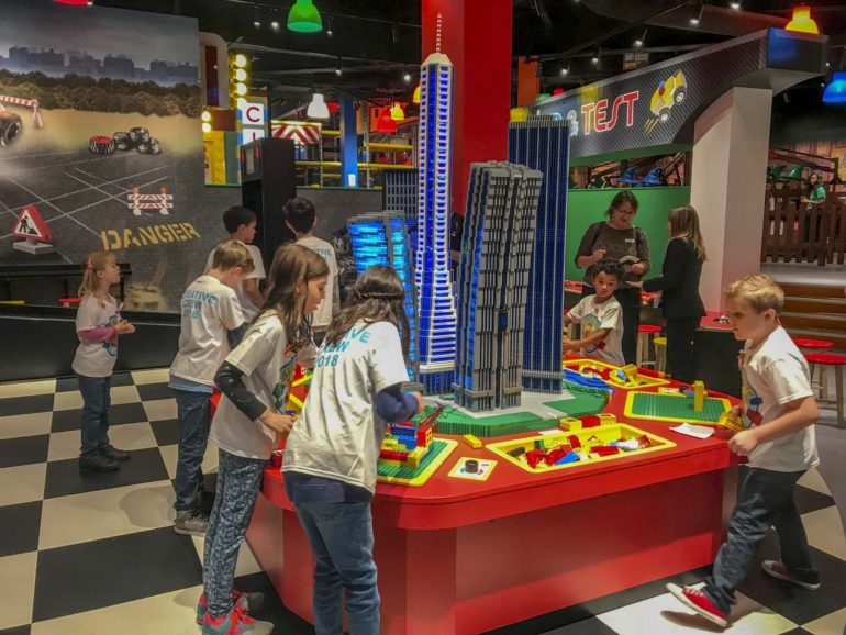 Children build a LEGO city skyline model at a hands-on table