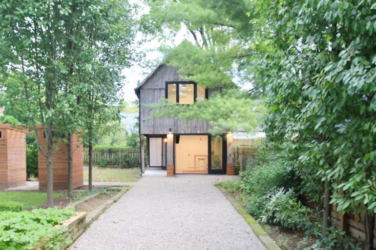 This Charming Granville Barn Is the Airbnb Of Your Dreams 1 Modern dark wood two-story house with large windows nestled among green trees and foliage.