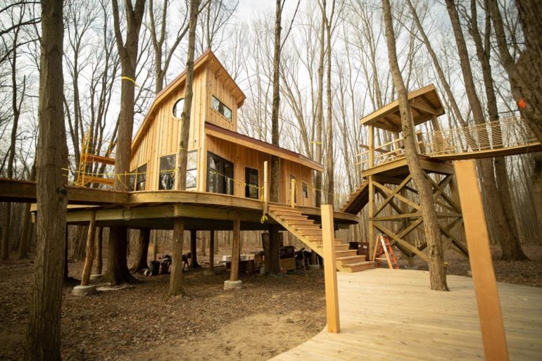 Wooden treehouse on stilts with elevated walkways among bare winter trees