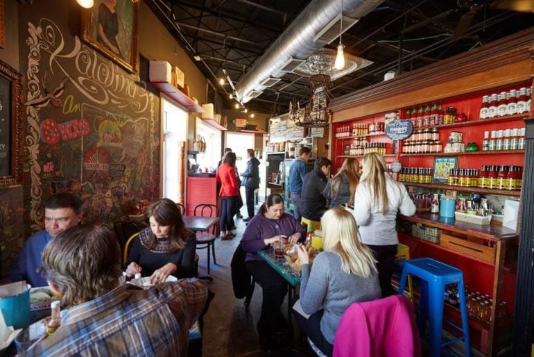 9 Tiny Columbus Restaurants That Prove Size Doesn’t Matter 17 Customers dining inside Katalina's, with a shelf of goods and chalkboard mural