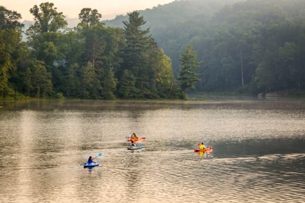 Kayakers paddling across misty Lake Hope surrounded by forested hills