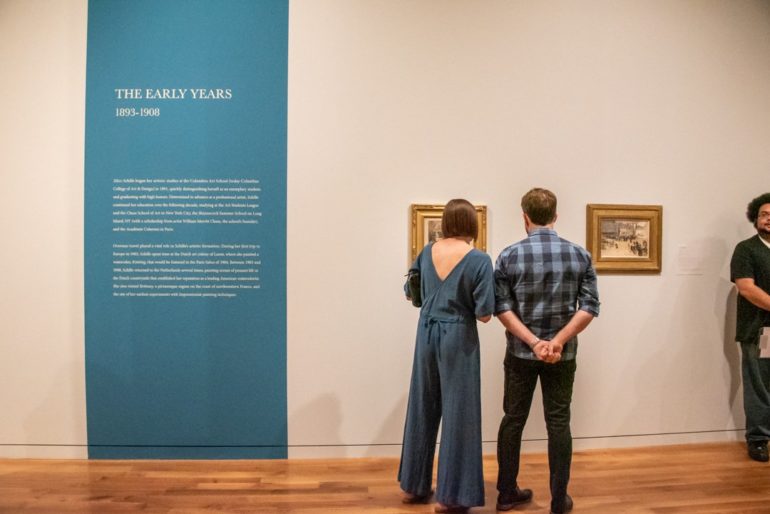Two visitors view framed artworks in a museum gallery labeled The Early Years 1893-1908