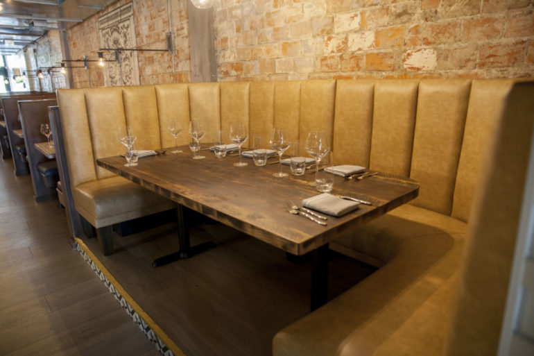 The Best Restaurants For Large Groups In Columbus 1 Long leather booth with wood table set for a group against exposed brick