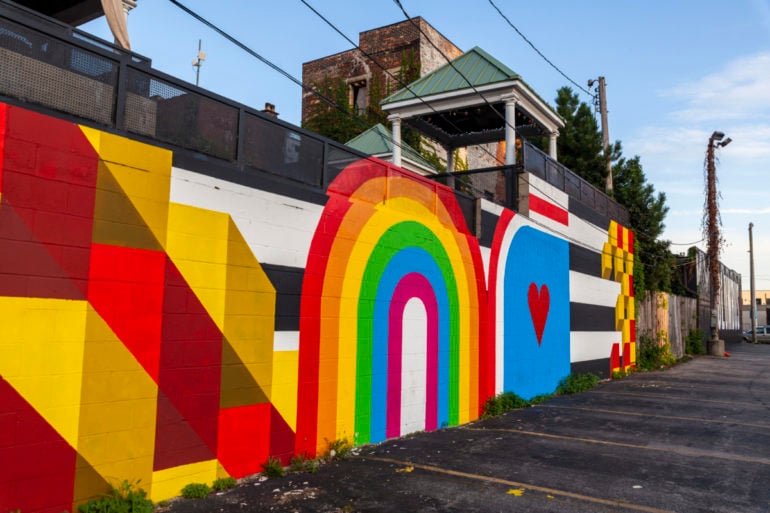 The Columbus Color Wall Mural Downtown Is The Happiest Photo Op In Town 4 Colorful mural with rainbow arch, red heart, and geometric patterns on brick wall