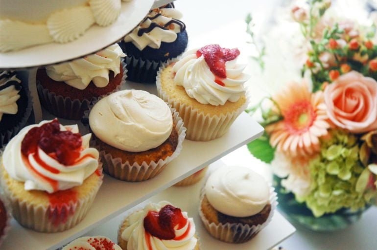 Assorted frosted cupcakes with fruit toppings from Fate Cakes