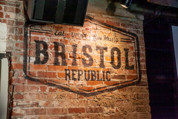 Weathered brick wall sign reading "Eat Drink Live Music" with "Brassy" and "Republic" text visible.