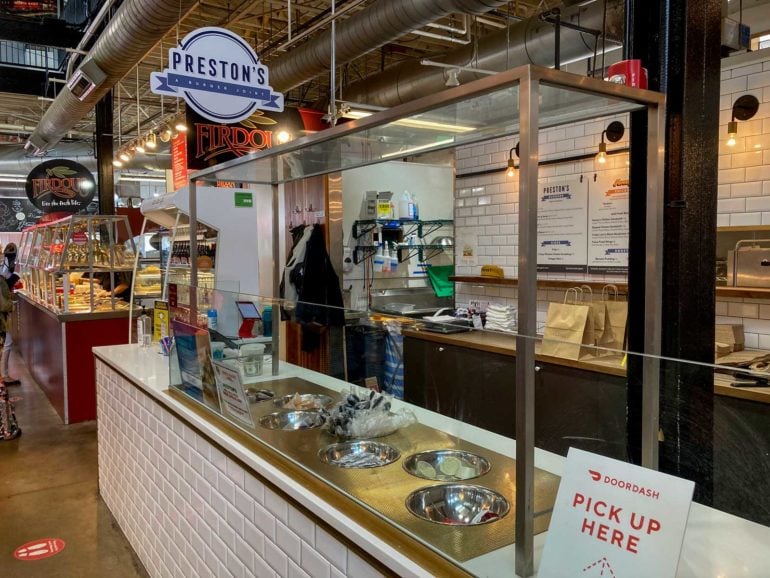 Preston's burger restaurant counter with DoorDash pickup sign and kitchen visible behind glass.