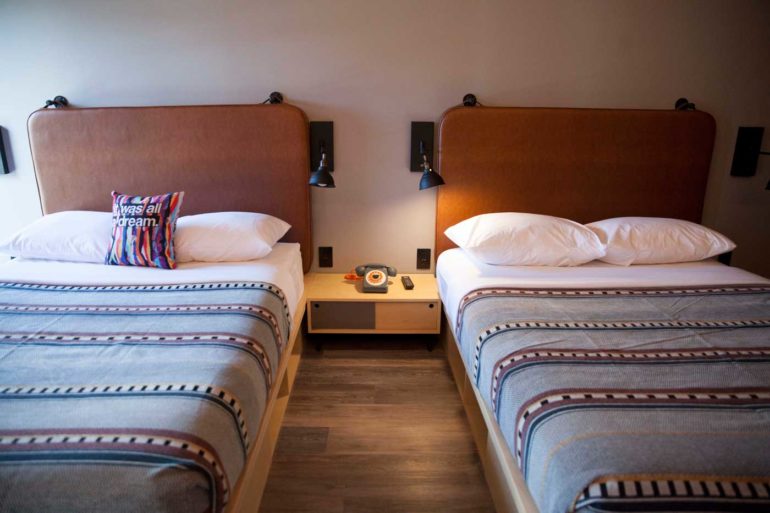 The Best Hotels In Downtown Columbus 3 Two twin beds with brown upholstered headboards and striped blankets at Moxy hotel