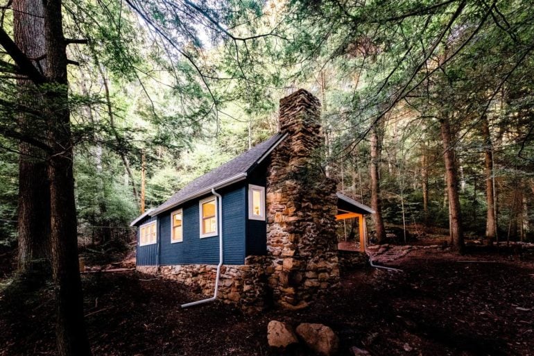Dunlap Hollow cottage with stone chimney nestled among Hocking Hills trees