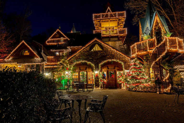 This Magical Christmas Castle Is The Perfect Way To Spend Time With The Family 3 Festive stone buildings decorated with golden lights and holiday wreaths at night