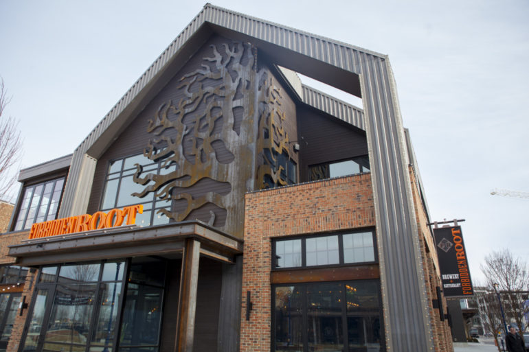 Forbidden Root At Easton Is The First Concept To Open In The New $500 Million Expansion 1 Modern brick and metal building with large decorative cutout and orange signage.
