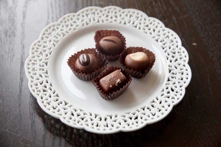 Four artisan chocolate truffles from Winans Chocolates + Coffees in paper cups on a decorative plate