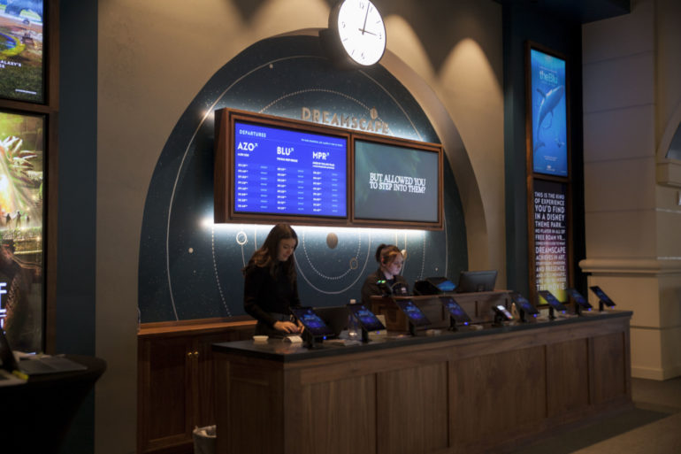The Virtual Reality Experience At Dreamscape Is The Coolest Thing You Can Do In Columbus Right Now 4 Themed ticketing counter with departure board screens and staff at service desk