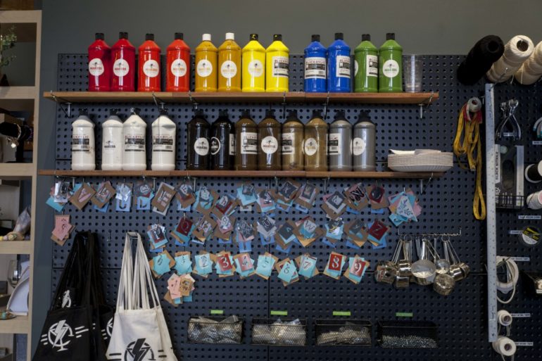 The Best Spots In Columbus To Craft With Friends 7 Shelves of colorful paint bottles and craft tags on a pegboard wall
