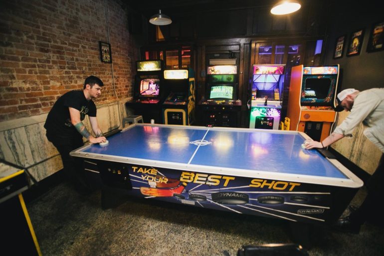 Two men playing air hockey at Old North Arcade