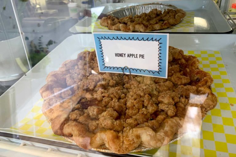 Honey apple pie with crumb topping on yellow checkered paper at Dough Mama