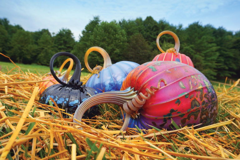 Glass-blown pumpkins nestled in straw at the Jack Pine Glass Pumpkin Festival