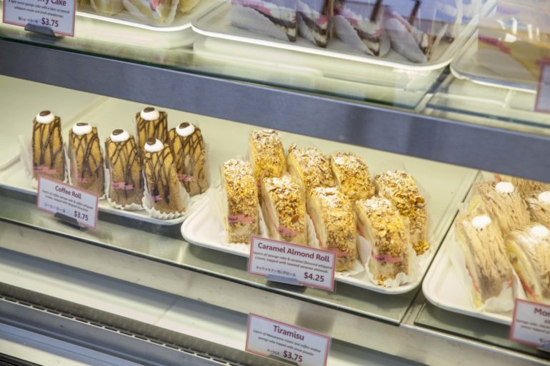 Belle's Bread Is A Delicious French-Inspired Japanese Bakery In A North Columbus Strip Mall 3 Bakery display case showing coffee rolls, caramel almond rolls, and tiramisu cake with price tags.