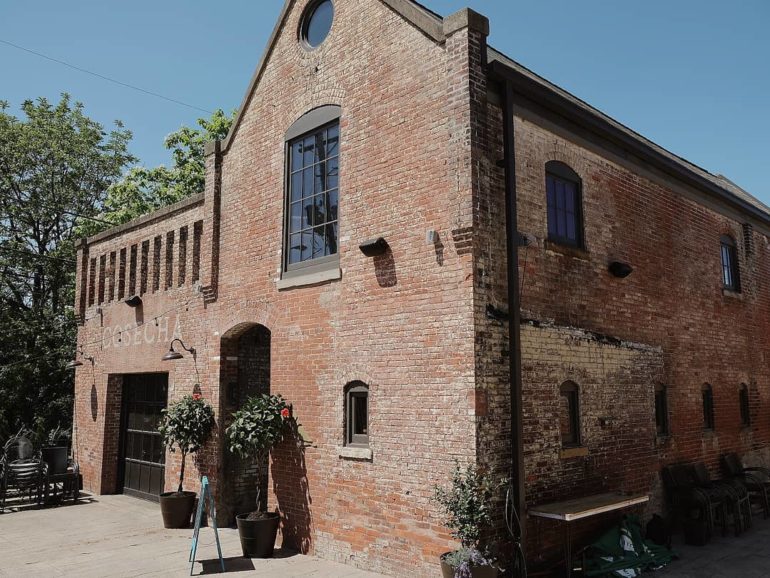 Historic red brick building with arched windows and circular opening under clear blue sky.