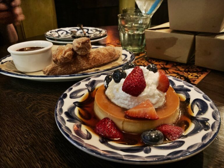 5 Must-Try Menu Items At CMR’s El Segundo 9 Flan topped with whipped cream and berries in caramel sauce, churros with chocolate dip behind