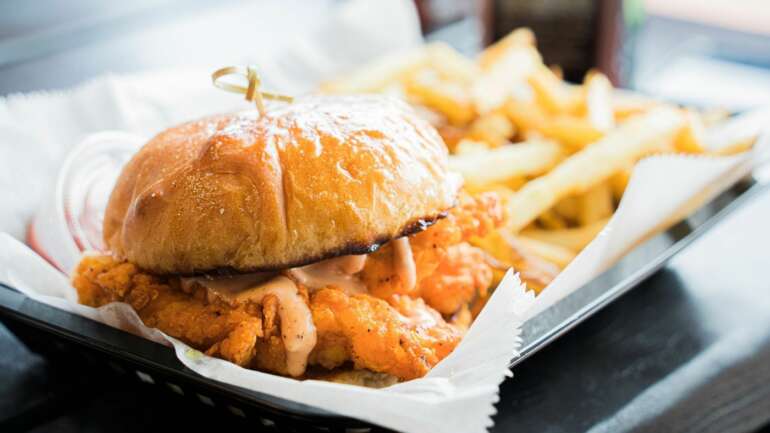4 Must-Try Chicken Sandwiches In Columbus 3 Just Chicken's fried chicken sandwich with sauce, served with fries in a basket
