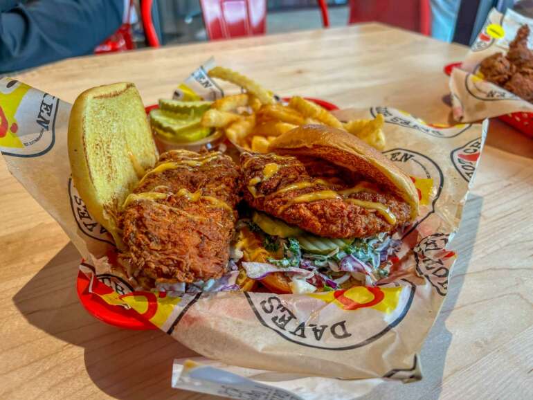 Fried chicken sandwich with pickles, coleslaw, and crinkle-cut fries in a basket