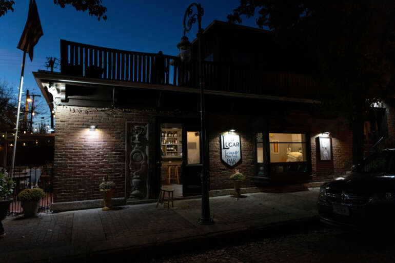 Evening exterior shot of a brick restaurant with illuminated storefront and "UGAR" signage visible.
