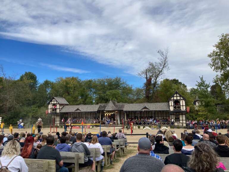 The 10 Best Things To Do At The Ohio Renaissance Festival 3 Crowd seated on benches watching a show at Tudor-style festival buildings