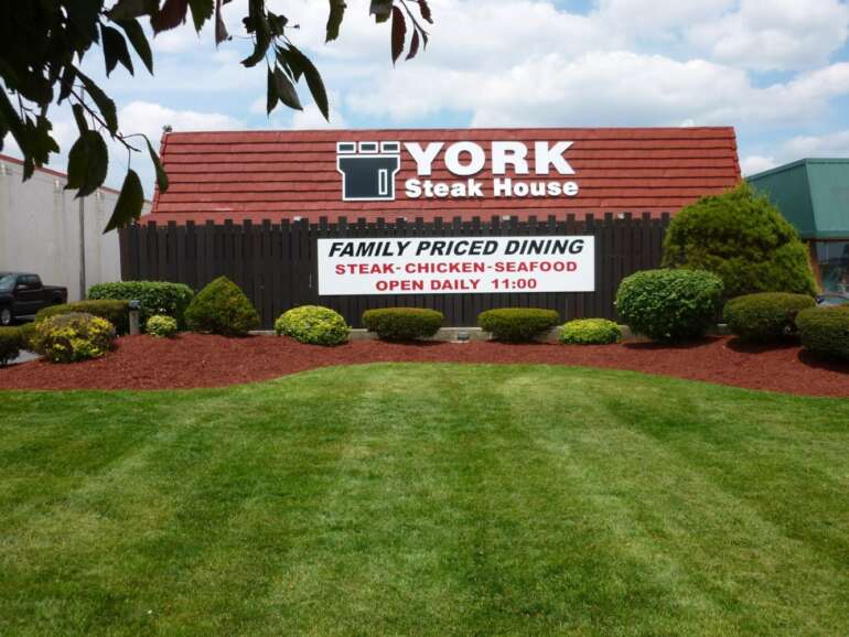 This Decades-Old Columbus Steak House Has A New Owner 2 York Steak House exterior sign with red roof and landscaped entrance