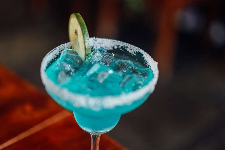 A blue non-alcoholic mocktail with lime garnish