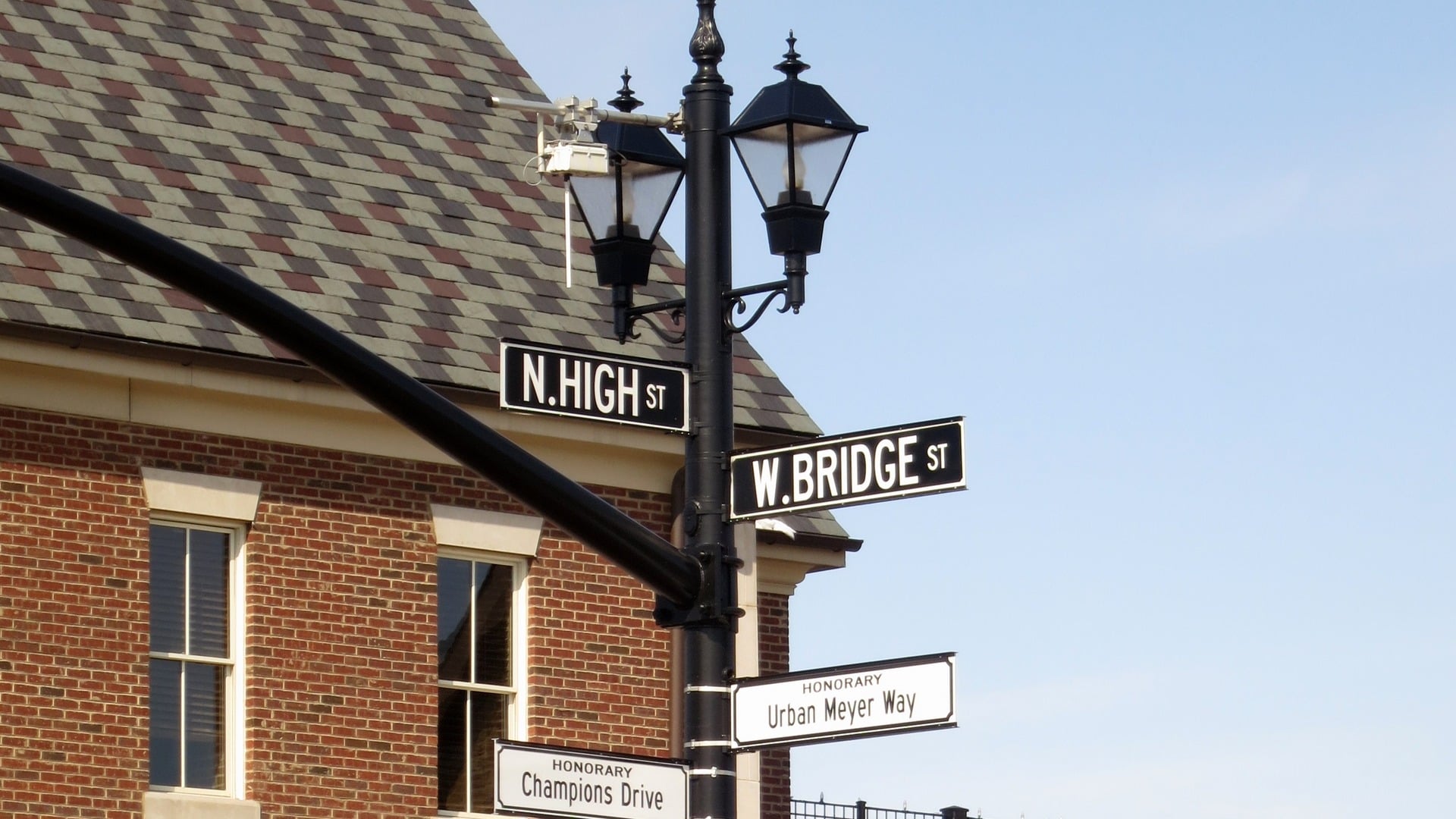 The N. High St. and W. Bridge St. street signs on a black lamp post in front of a brick building in Historic Dublin, Ohio