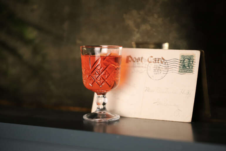 How A Former Post Office Became Westerville’s Newest Speakeasy 5 cocktail in front of vintage postcard