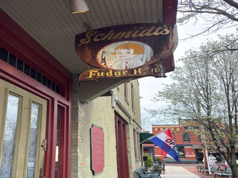 Vintage neon sign for Schmidt's restaurant with faded girl illustration hanging above storefront entrance.