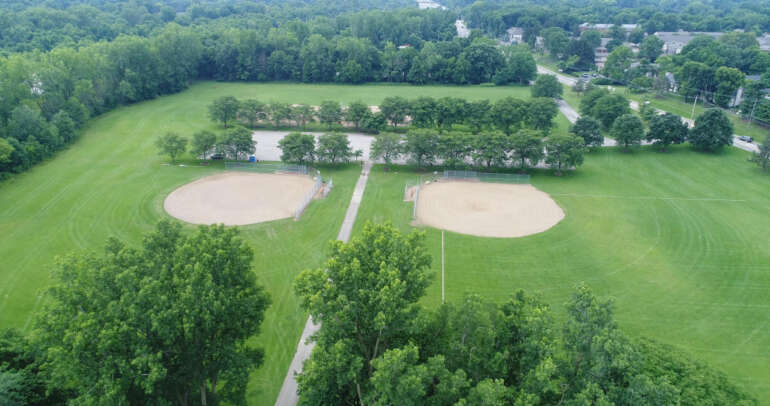 Columbus Dinks Into Summer With New Pickleball Courts At Anheuser-Busch Sports Park 6 Aerial view of two baseball fields with manicured grass and surrounding trees near a pond.