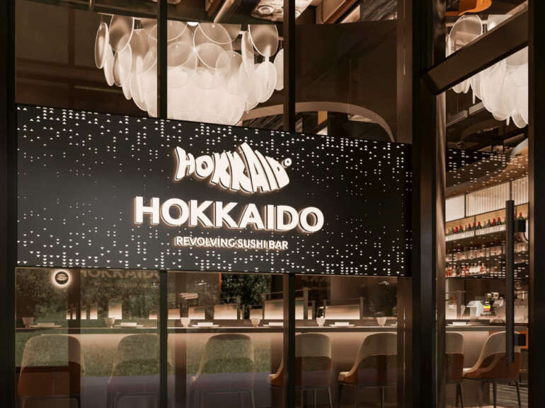 An All-You-Can-Eat Revolving Sushi Bar Is Coming To Columbus 4 Hokkaido Revolving Sushi Bar storefront with illuminated signage and modern interior seating visible through windows.