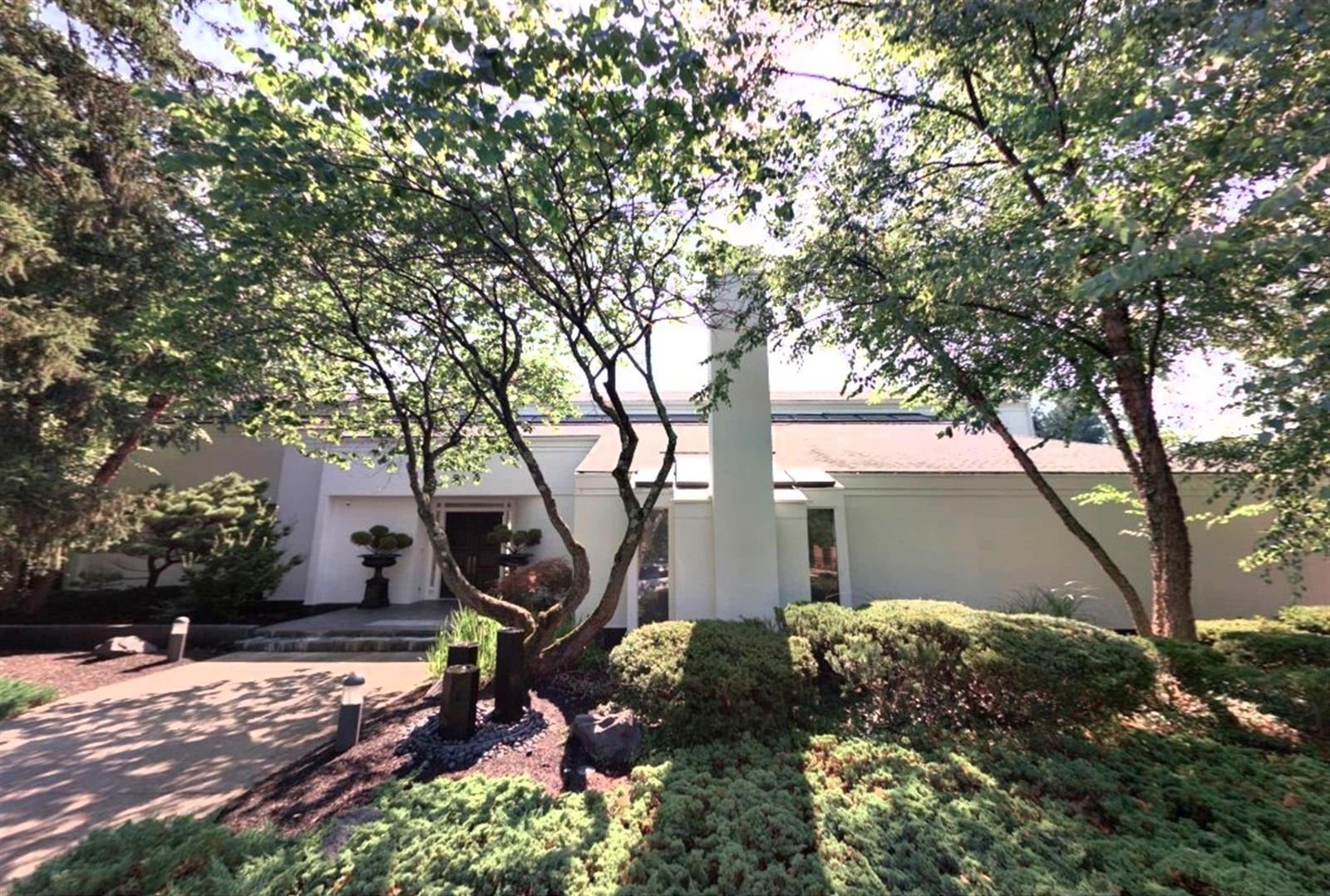 white modern house with a tall chimney seen through trees bexley ohio