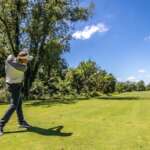 Ohio Just Created A Massive Golf Trail With 182 Public Courses Man mid swing at Hueston Woods Golf Course